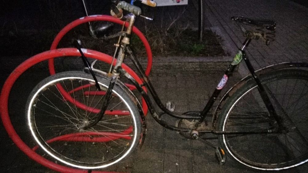 Ein sehr, sehr altes Fahrrad, mit Schloß am Fahrradständer gesichert.