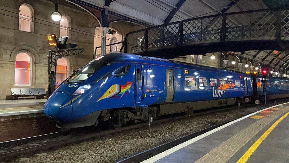 front view of blue lumo train with wavy intersex progress flag on the front of train
