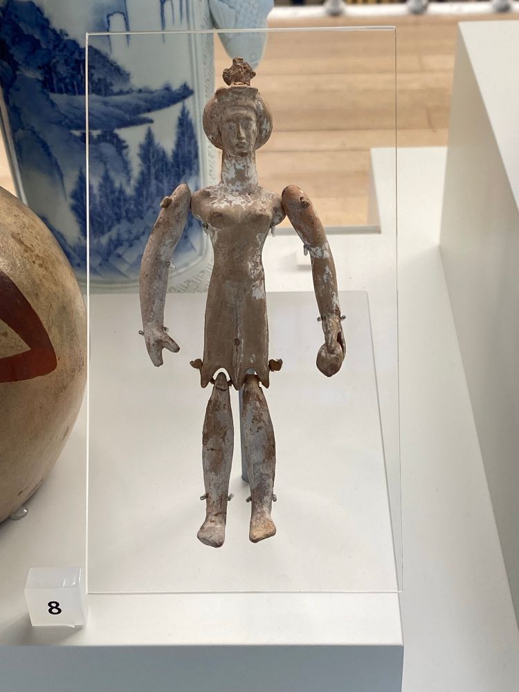 Ceramic jointed doll of a woman with elaborate hair and a tiara. 