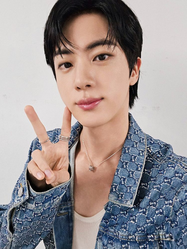 Seokjin in his coordinated sparkly denim Gucci stage outfit holding up a peace sign