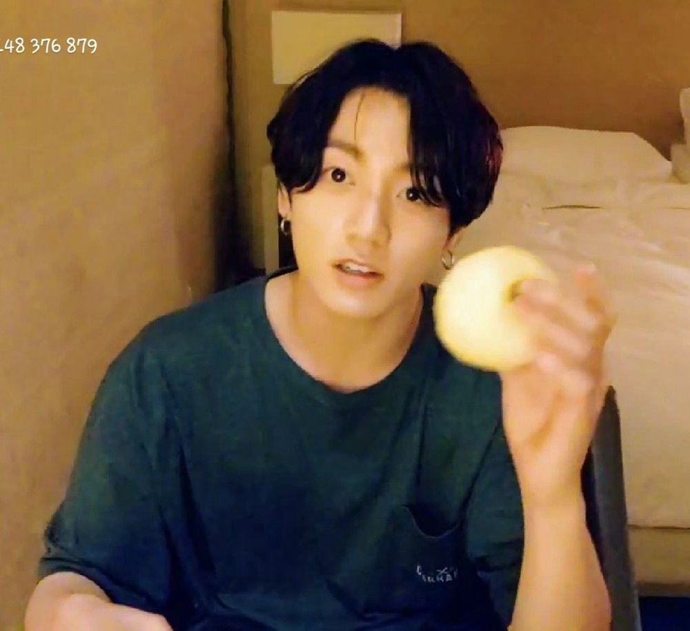 Jungkook in dark gray shirt hanging out with apple in his hotel room