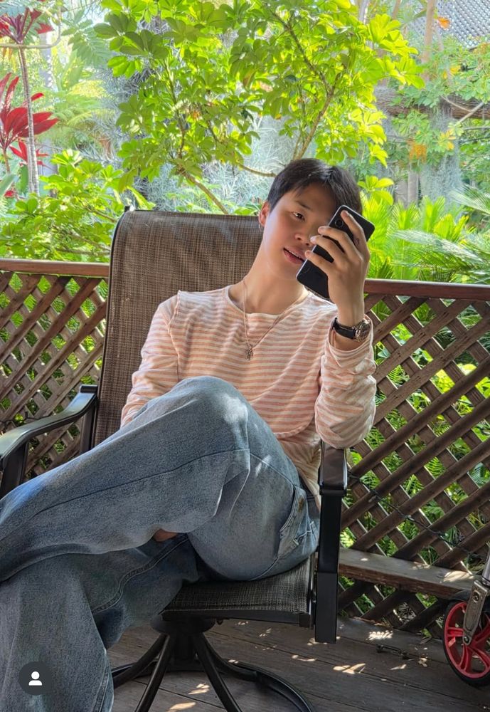 Jimin on his phone, sitting outdoors