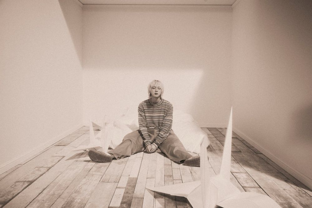 Blonde seokjin sitting on the floor with his legs sprawled out