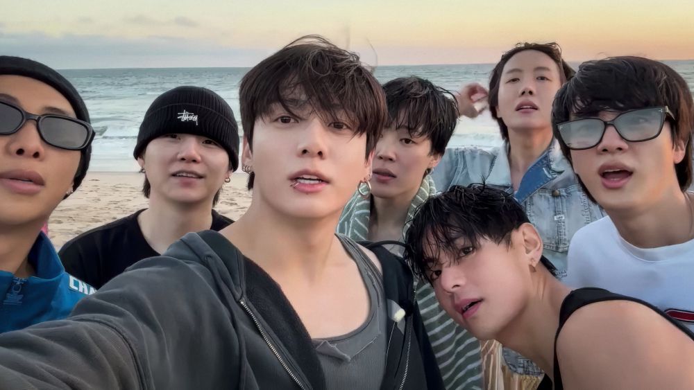 BTS Group photo at the beach. They’re all dressed in their relaxed casual vibe, perfect for a quick dip and sloshing around the ocean— esp Jimin 🤭 