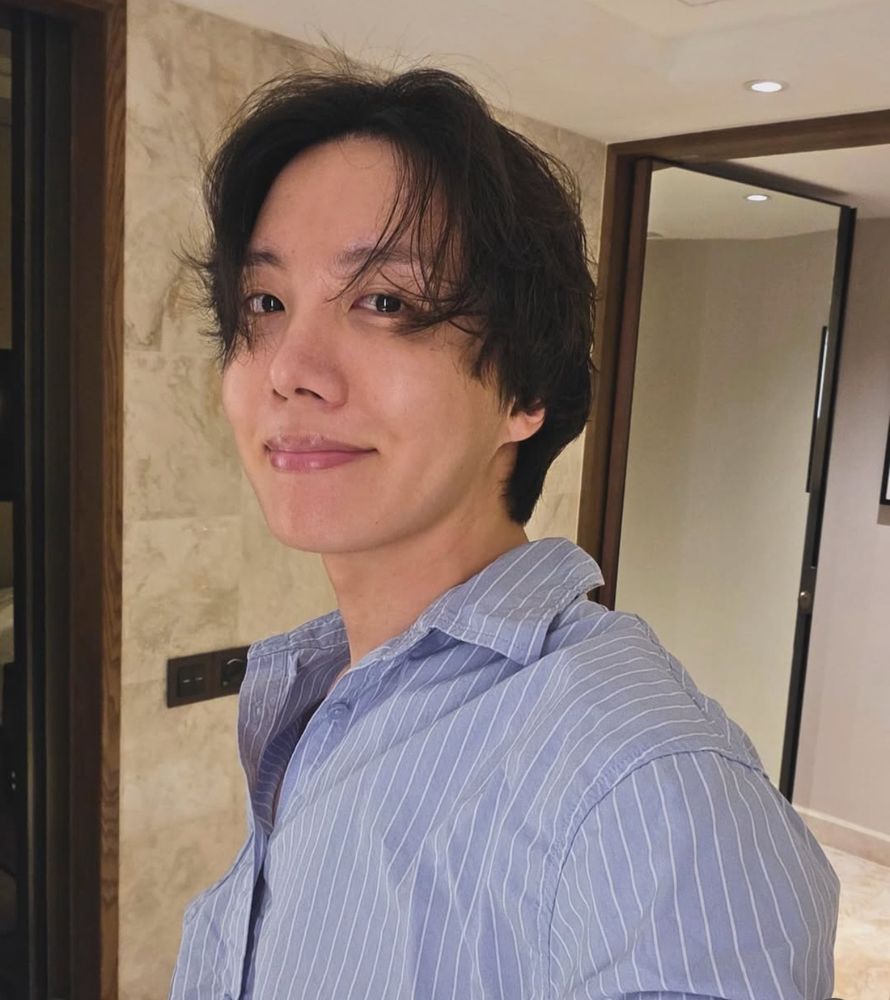 Hobi in his light blue pinstripe top leaning to the side