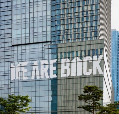 WE ARE BACK with BTS and ARMY logos decals on the HYBE building
