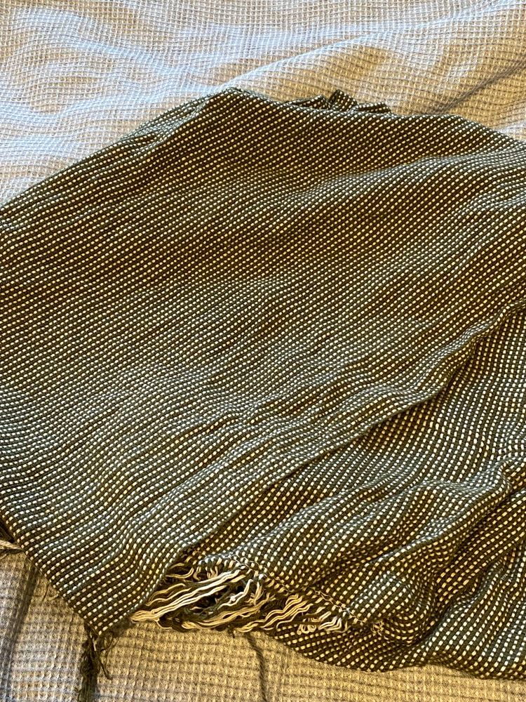 Some beautiful green and white hand-woven fabric folded on a bed