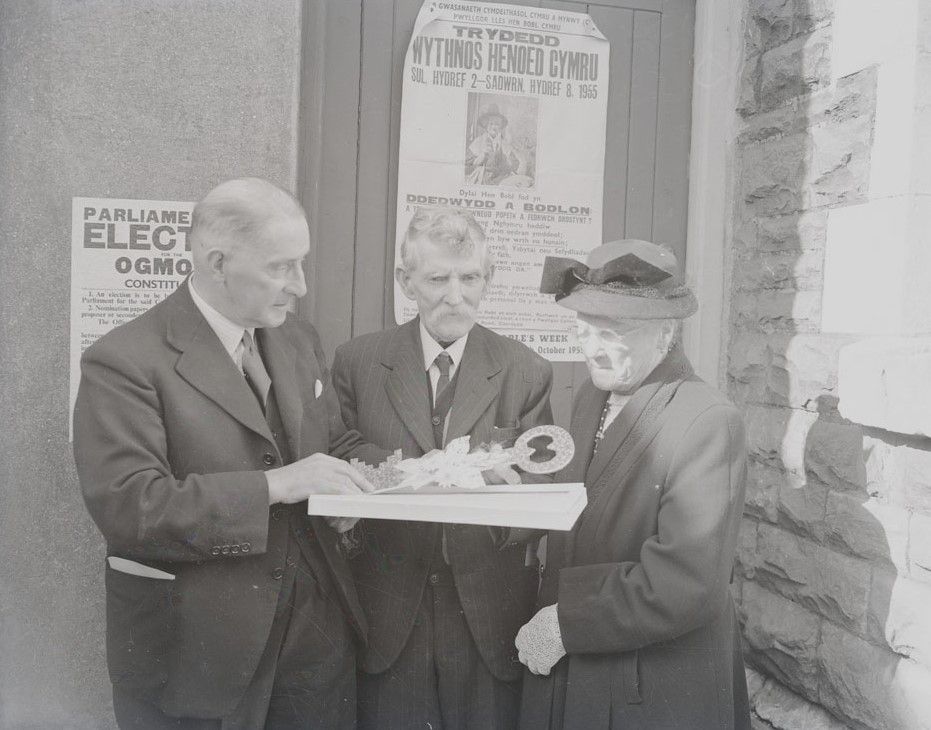 Three people standing around a box which holds a large ceremonial key.