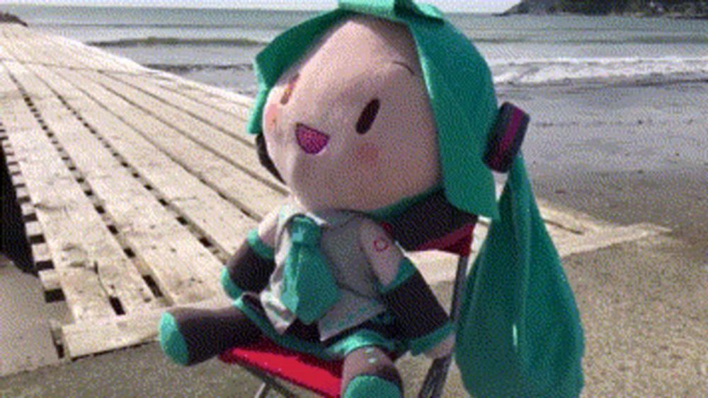 a stuffed animal with green hair is sitting on a chair on the beach .