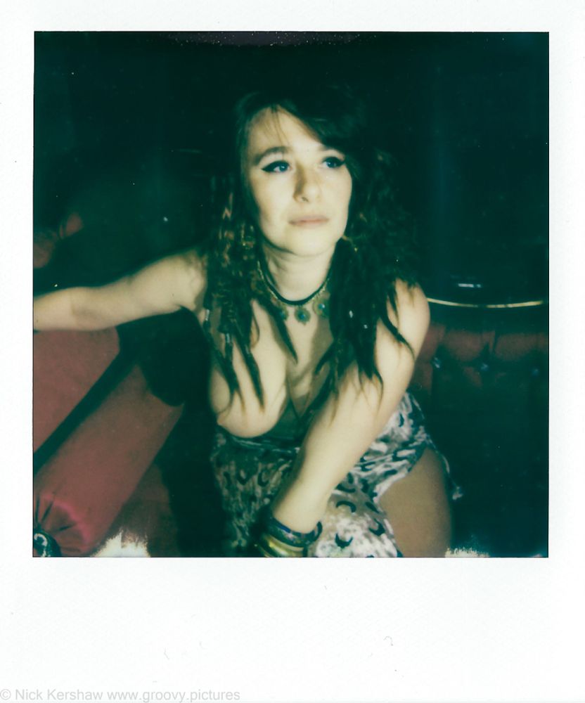 Polaroid of young woman with exposed breast sitting on a chaise longue