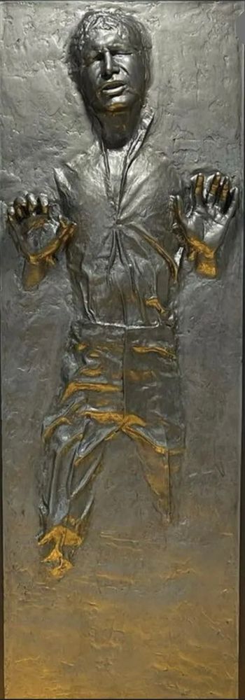 Statue of Han Solo with his hands raised, frozen in carbonite from the Star Wars films. 
