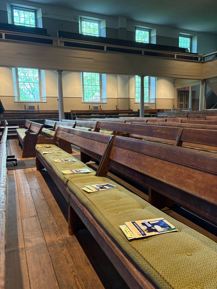 Quaker Meeting House with wooden pews and green cushions. 