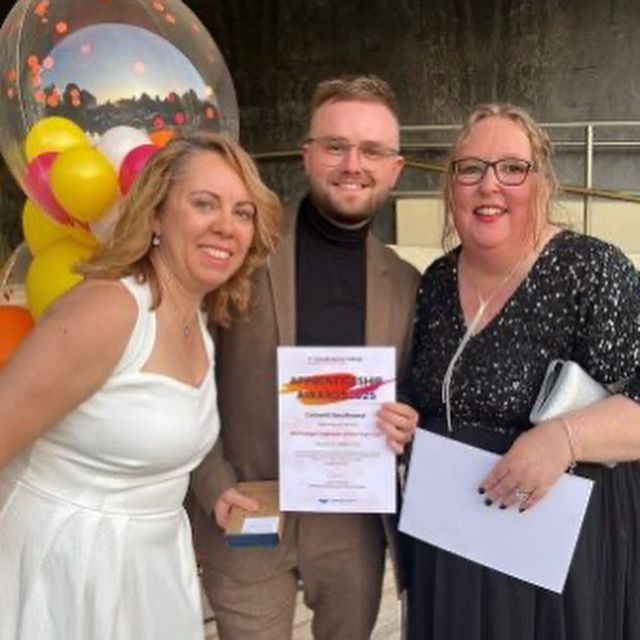 Two women and one man smiling holding a certificate 