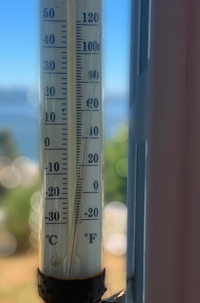 A thermometer in a window. The center gauge is broken and listing to the side 