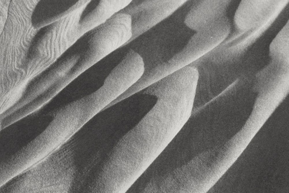 An archive photograph of waves of sand flowing diagonally across the frame.