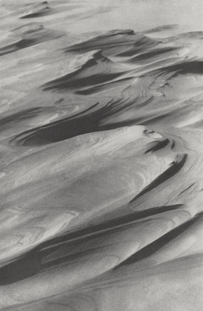 An archive photograph of waves of sand forming layered formations on a dune.