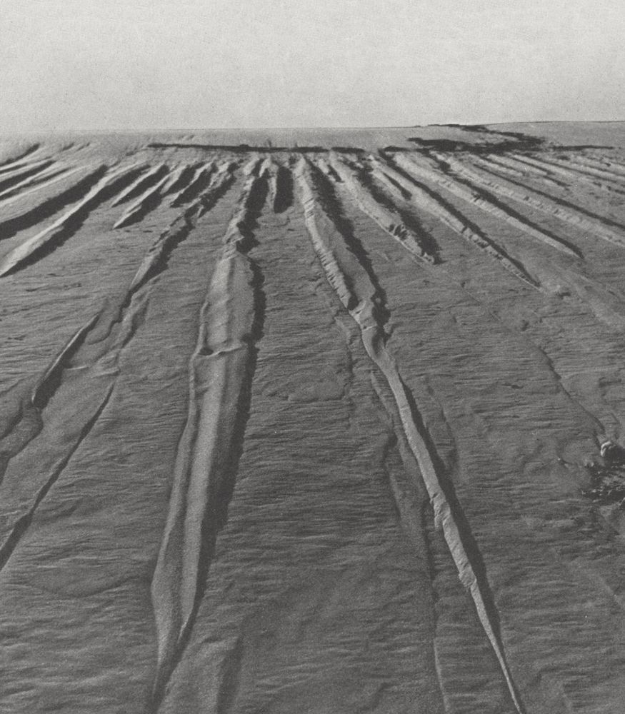 An archive photograph of vertical breaking lines in a large and tall facing sand dune.