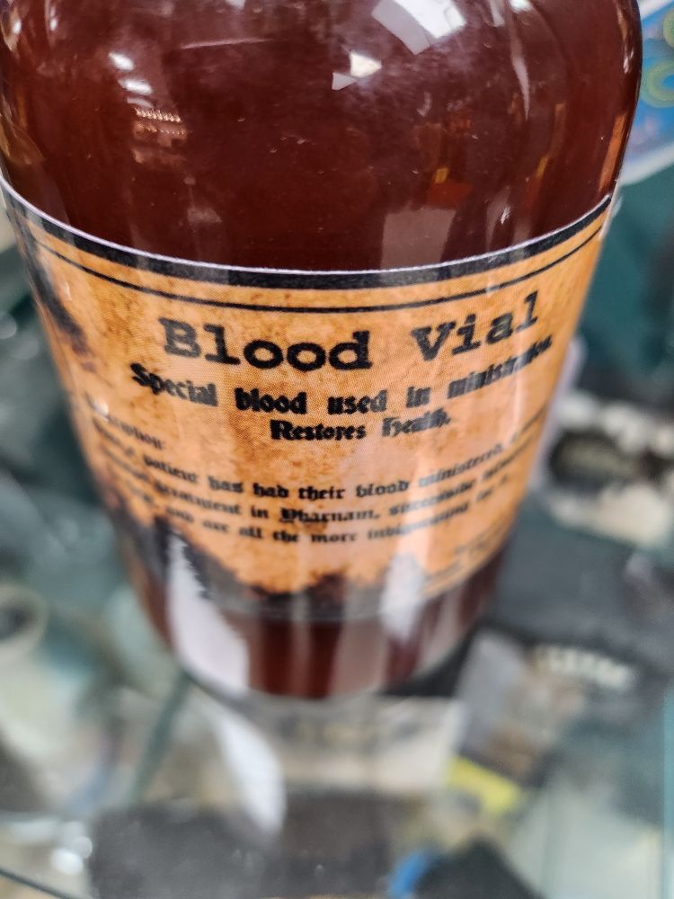 a close-up of the orange label of the "Blood Vial" that says: "Special blood used in ministration. Restores health." (Bloodborne game text)