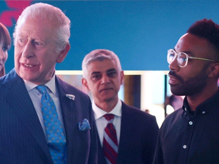 King Charles converses with Damien Roach at SXSW Festival, with Mayor Sadiq Khan also present in the background.