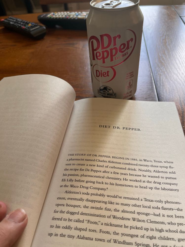 A photo of John Green’s book The Anthropocene Reviewed, held open to the essay titled “Diet Dr Pepper”, with a can of Diet Dr Pepper in the background. 