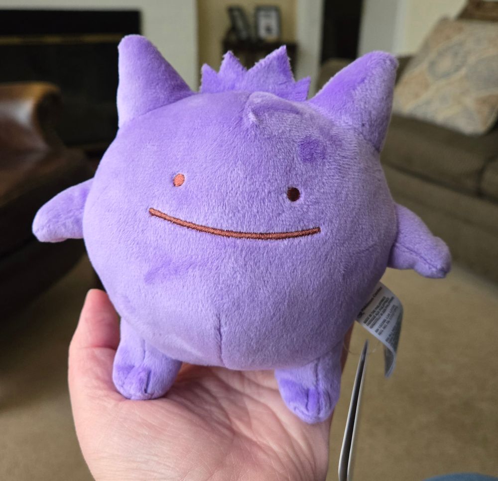 A plush toy of Gengar, very round purple boy with a simple smiley face