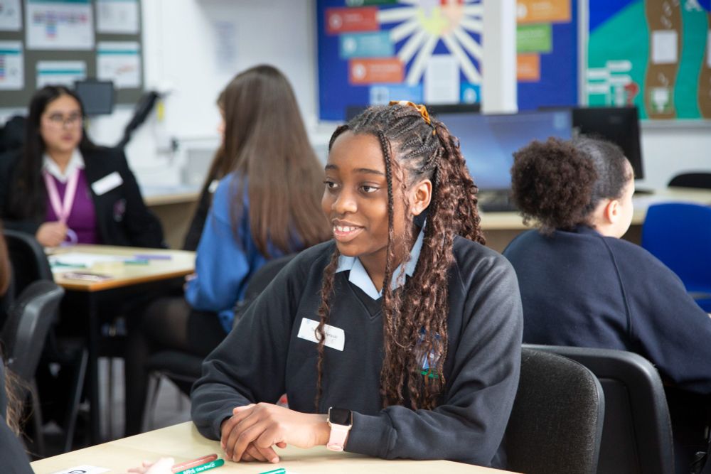 Student from Kings Norton Girls' School smiling towards another student out of frame.