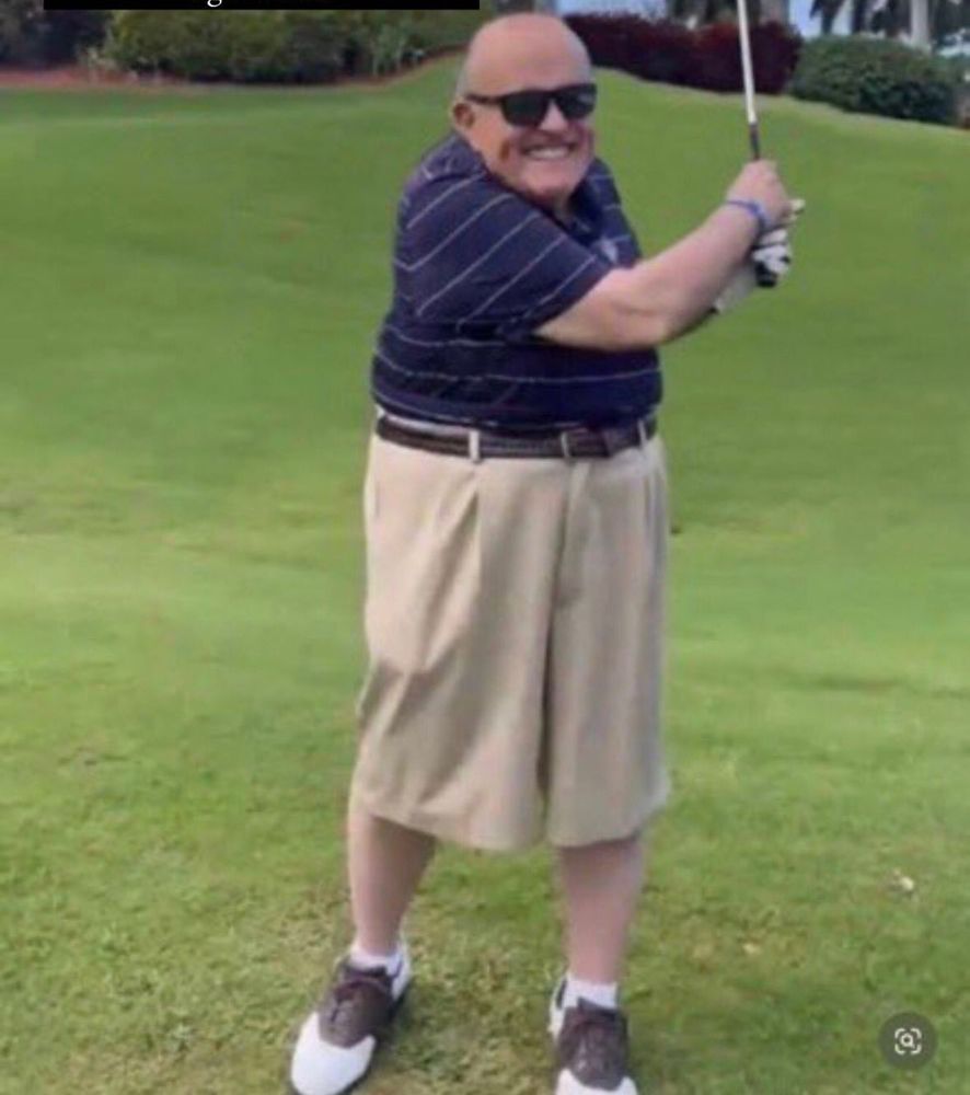 Rudy Guiliani on a gold course Swinging a club