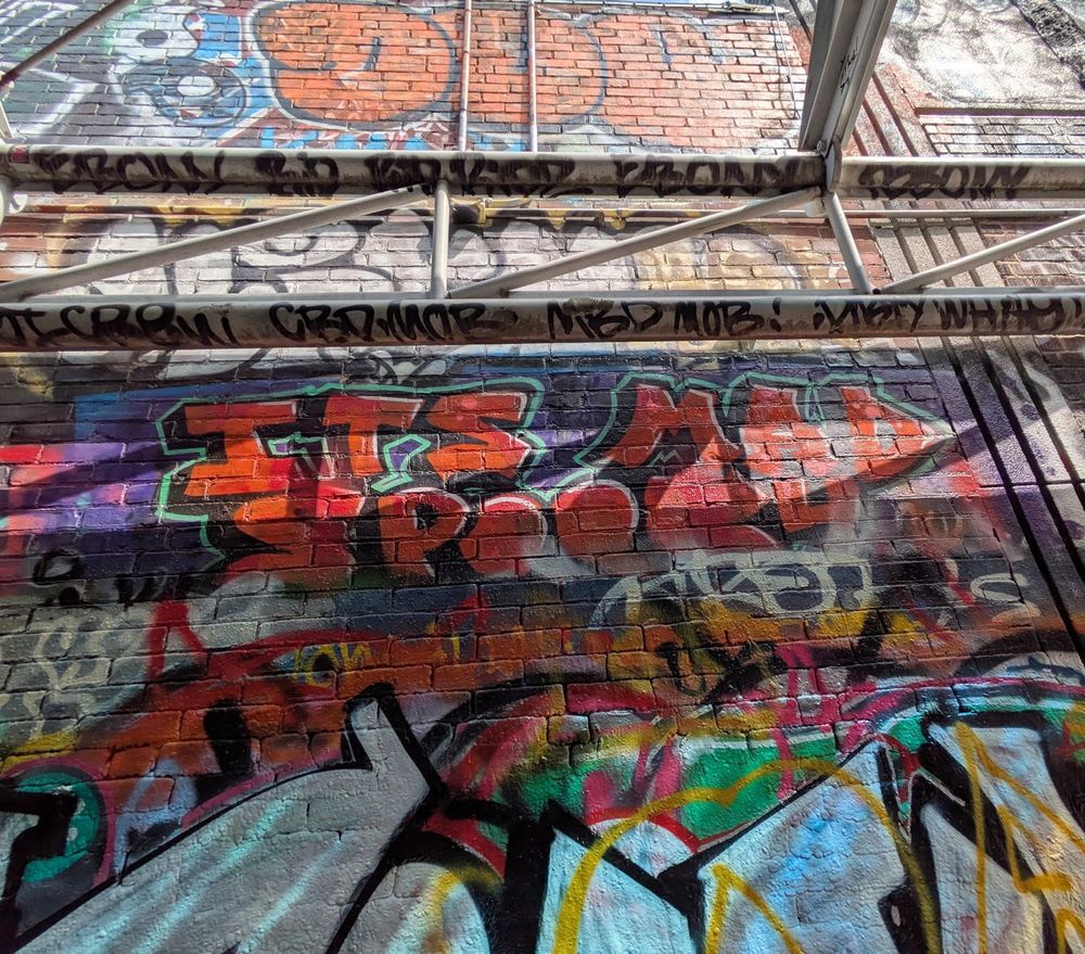 Misc paintings and text tags on wall, looking up towards skylight