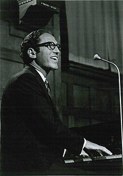 A black and white photo of Tom Lehrer playing the piano