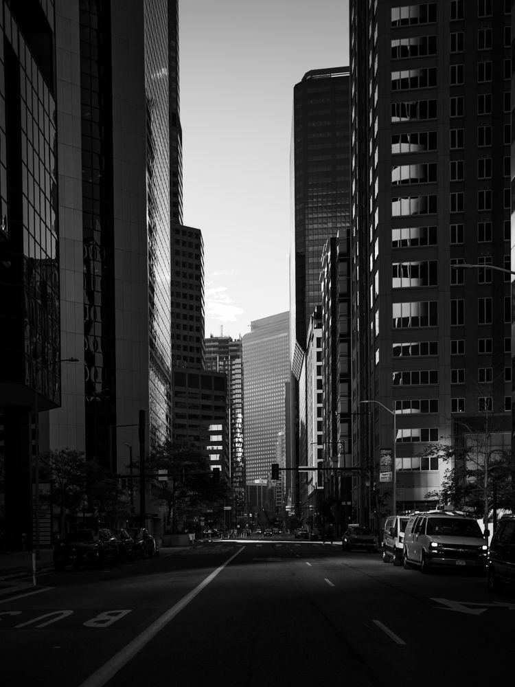 Early morning photo looking down 18th Street in Denver. Light and shadows appear on the high rises and the street