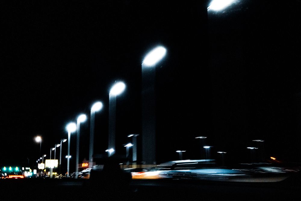 A long stretch of street lights down the right side of a road at night