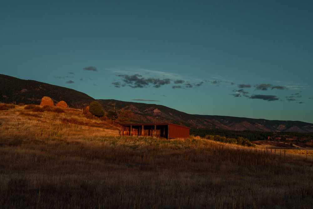 A red shed is lit up by morning sun just coming over the horizon