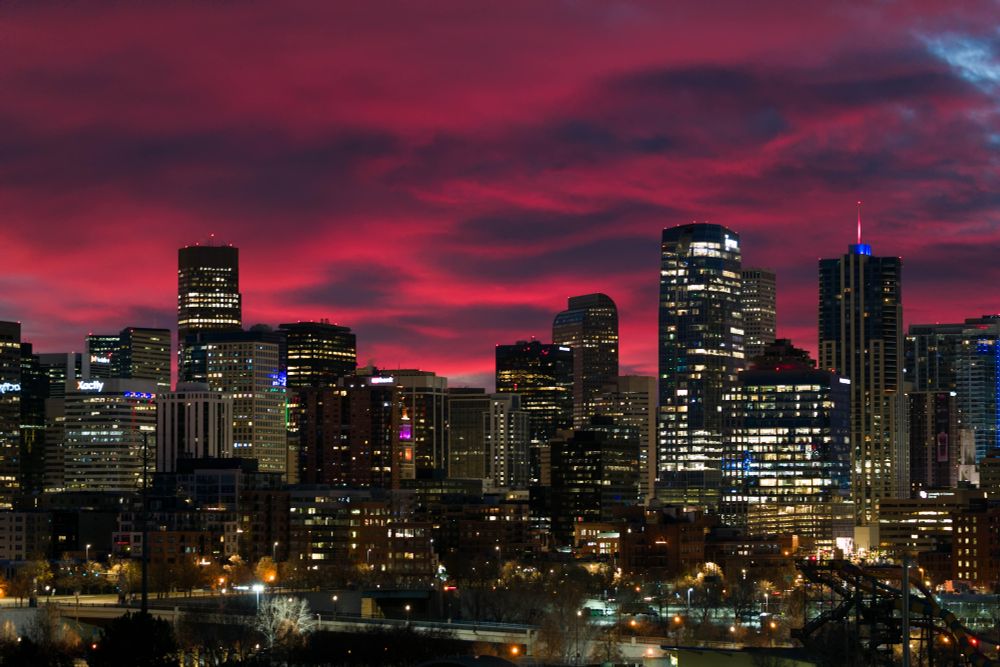 The sky over downtown Denver is glowing bright pink in the pre-dawn light