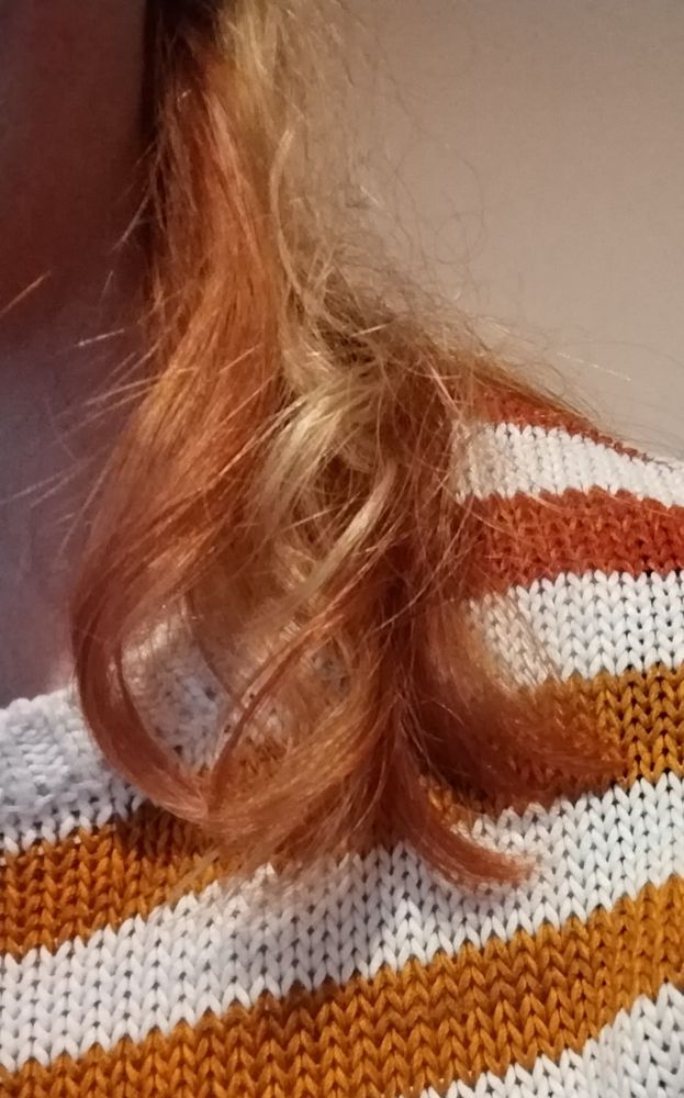 Longish hair, dyed blond and red, against a white, red and orange striped jumper. 