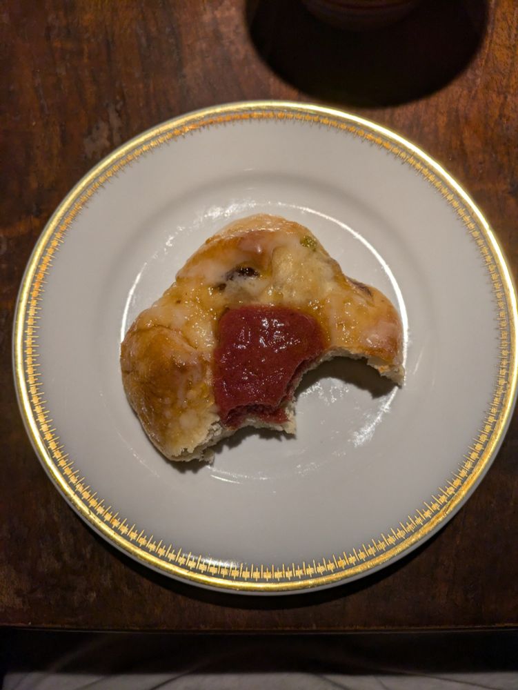 Ein angebissenes Reformationsbrötchen auf einem Goldrandteller.