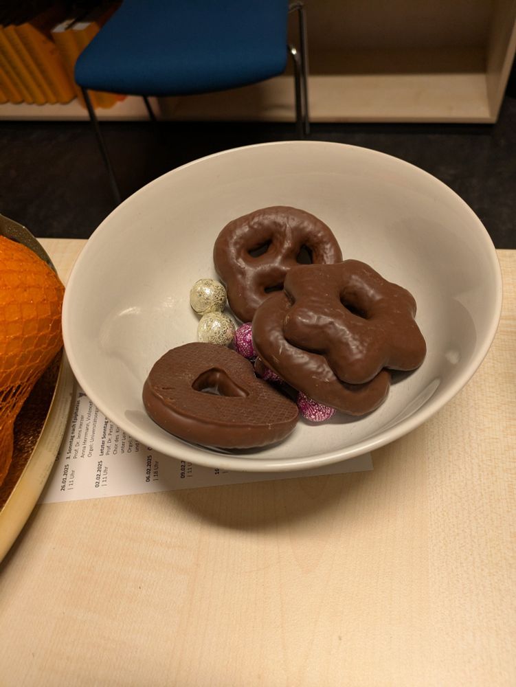 A bowl with leftovers from the team meeting yesterday on my desk containing chocolate and gingerbread.