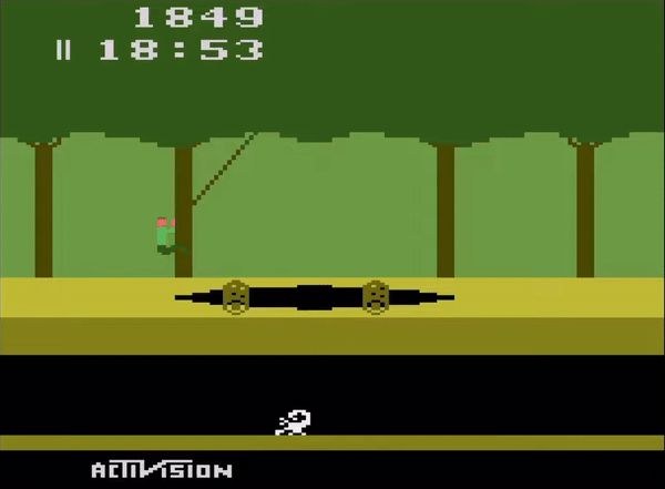 cenas do jogo Pitfall!: a imagem é dividida em duas partes horizontais: na parte superior o fundo é verde, representando fileiras de árvores de tronco marrom escuro e copas unidas; a parte de baixo da imagem é um subsolo de fundo preto onde anda um grande escorpião branco. Na primeira cena, há no primeiro plano um pequeno homem saltando com um cipó um grande buraco escuro no chão e há também troncos de árvore rolando pelo chão que ele salta; na segunda cena, o hominho precisa atravessar um lago pulando na cabeça de 3 jacarés, mas é engolido pelo terceiro.
