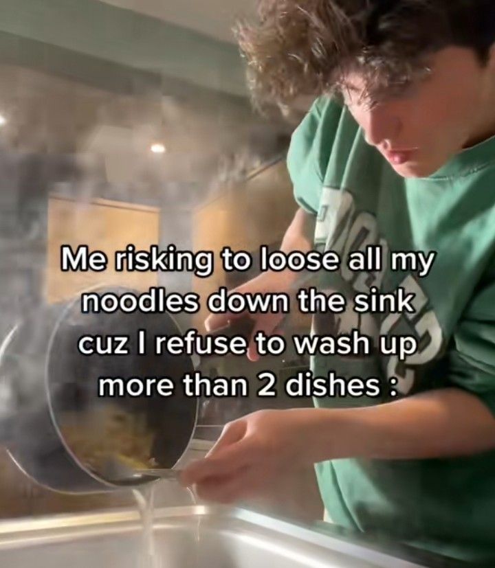 A person in a green sweatshirt is seen pouring hot water and noodles from a pot into a sink, using the pot's lid to strain the noodles instead of a proper strainer. Steam rises from the sink.

Overlaid text reads: “Me risking to loose all my noodles down the sink cuz I refuse to wash up more than 2 dishes”