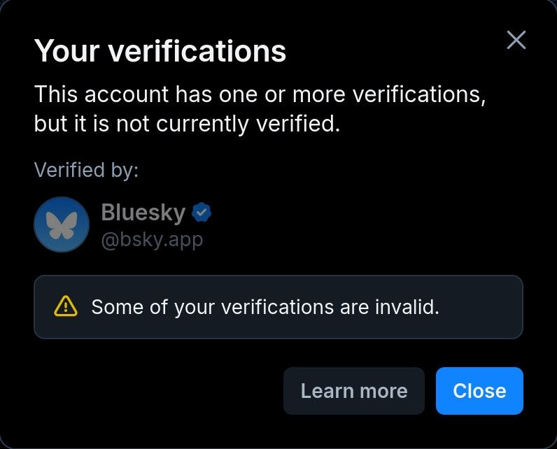 Pop-up modal: Jendela notifikasi verifikasi akun Bluesky yang menyatakan: 'Akun ini memiliki satu atau lebih verifikasi, tetapi belum terverifikasi untuk saat ini.'

Di bawahnya terdapat peringatan berikon segitiga kuning yang bertuliskan: 'Beberapa verifikasi Anda tidak valid.'

Terdapat dua tombol di bagian bawah: 'Pelajari lebih lanjut' dan 'Tutup'."