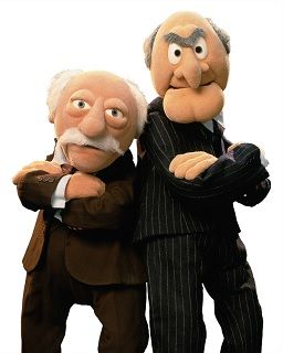 Picture of the 2 old white guy critics in the Muppets Show standing with their backs together folding their arms like gangsters