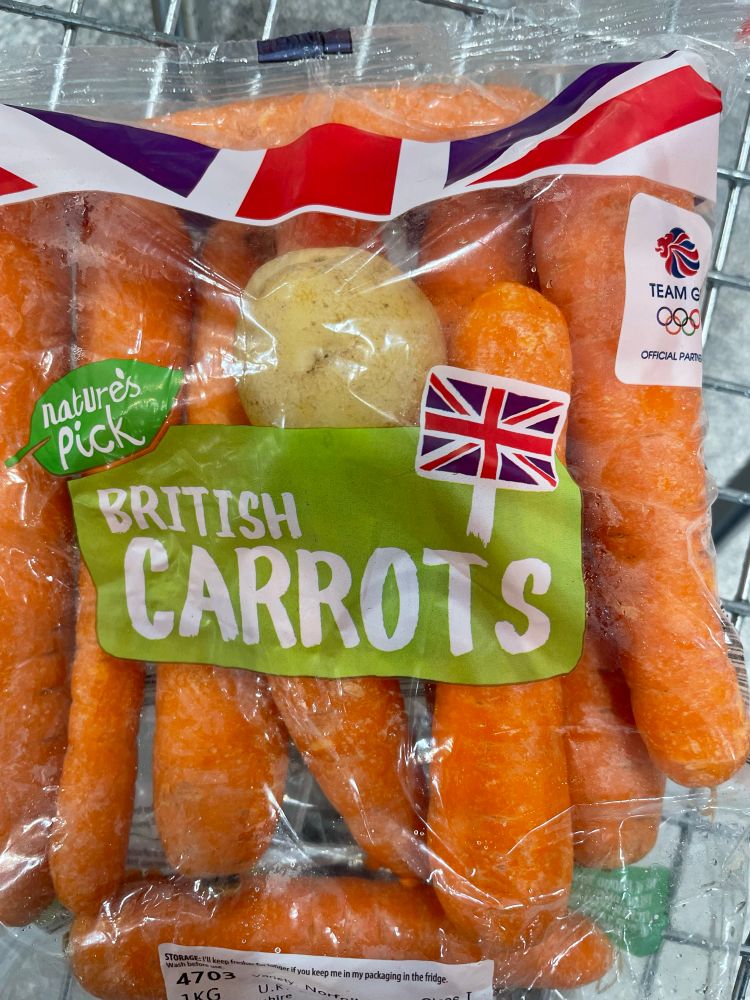 An unopened bag of carrots with a solitary potato inside 
