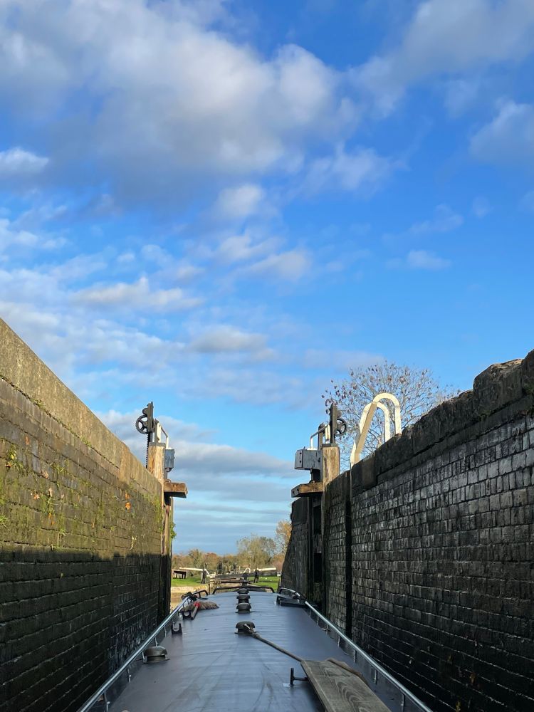 Narrowboat leaving one of the locks at Hurleston Junction 
Lock gates open, a blue sky above