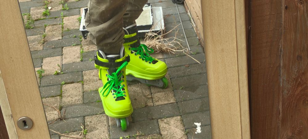 A picture of a mirror in which is reflected my feet which are clad in neon green jet set radio rollerblades