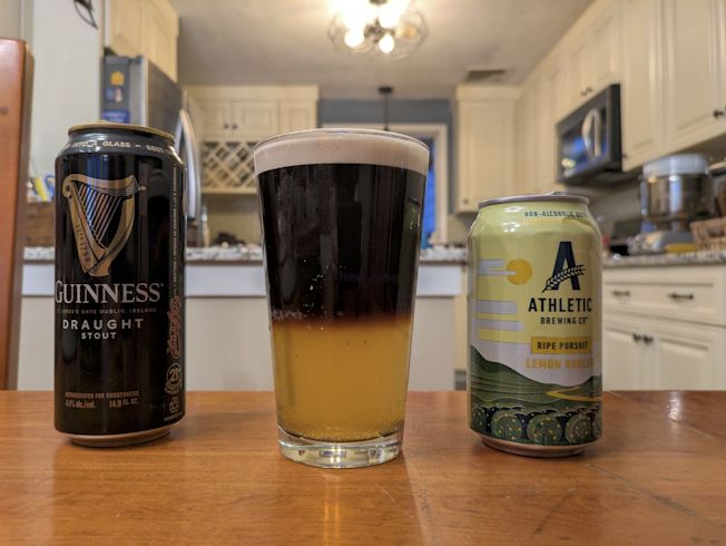 Half and half glass of Guiness Stout and Athletic non-alcoholic, lime flavored beer.