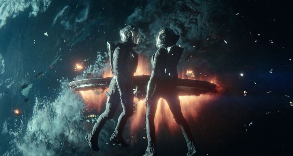 Spock and Chapel wearing white EV suits in space, an explosion in the background 