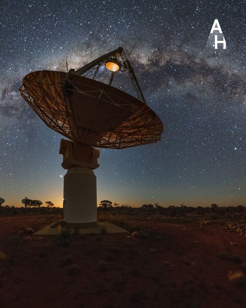A telescope dish in the outback under a starry sky