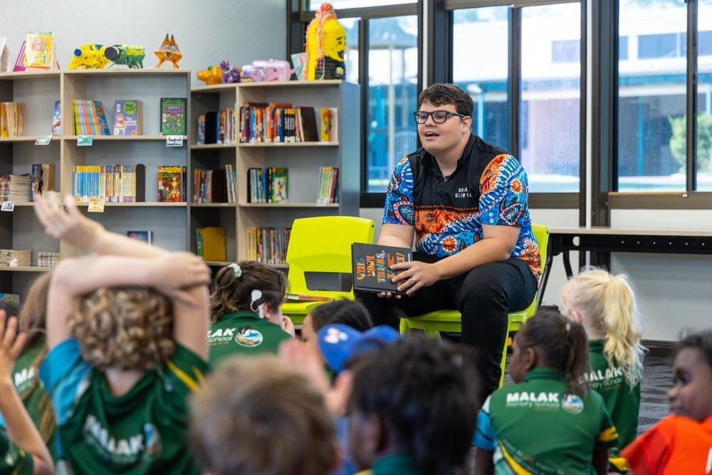 Man with glasses discusses a book with students at a school