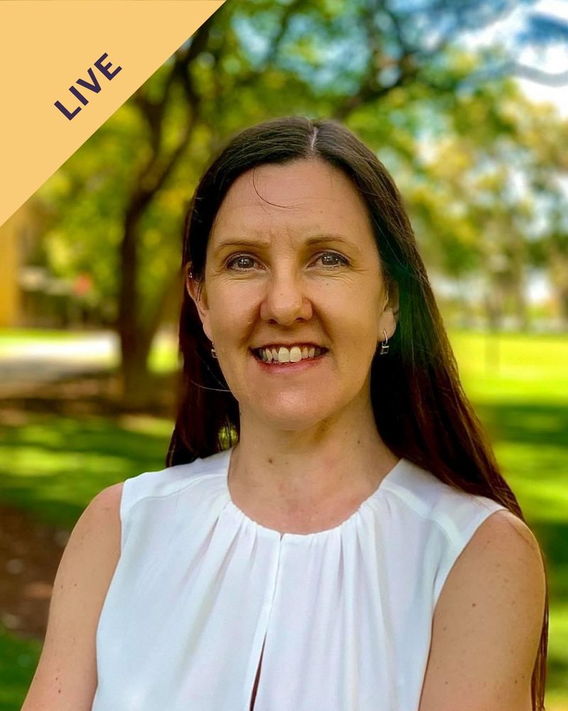 Woman with dark hair in white shirt in a natural landscape smiles at the camera.