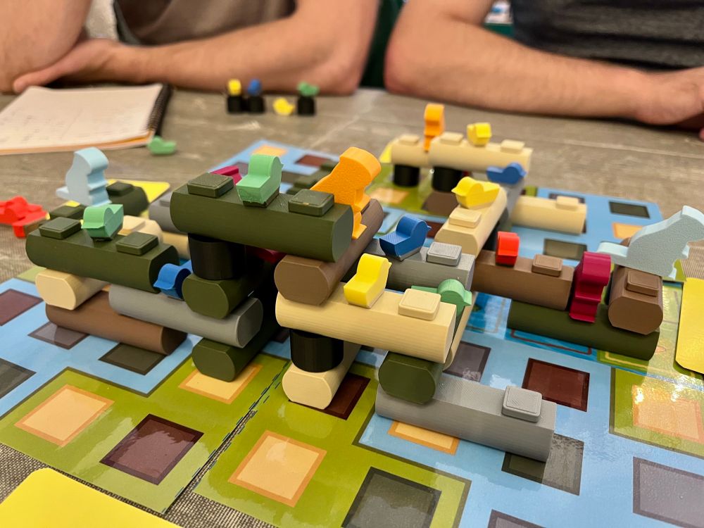 A picture of a board game in progress. A number of 3D-printed logs are stacked up across the board, with beavers and birds sat upon them. 