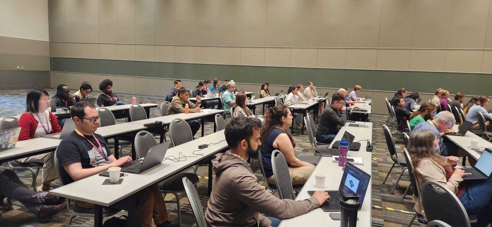 A wide view of the same workshop room, showing attendees seated and focused on their laptops during the Pixi machine learning workshop at SciPy 2025.
